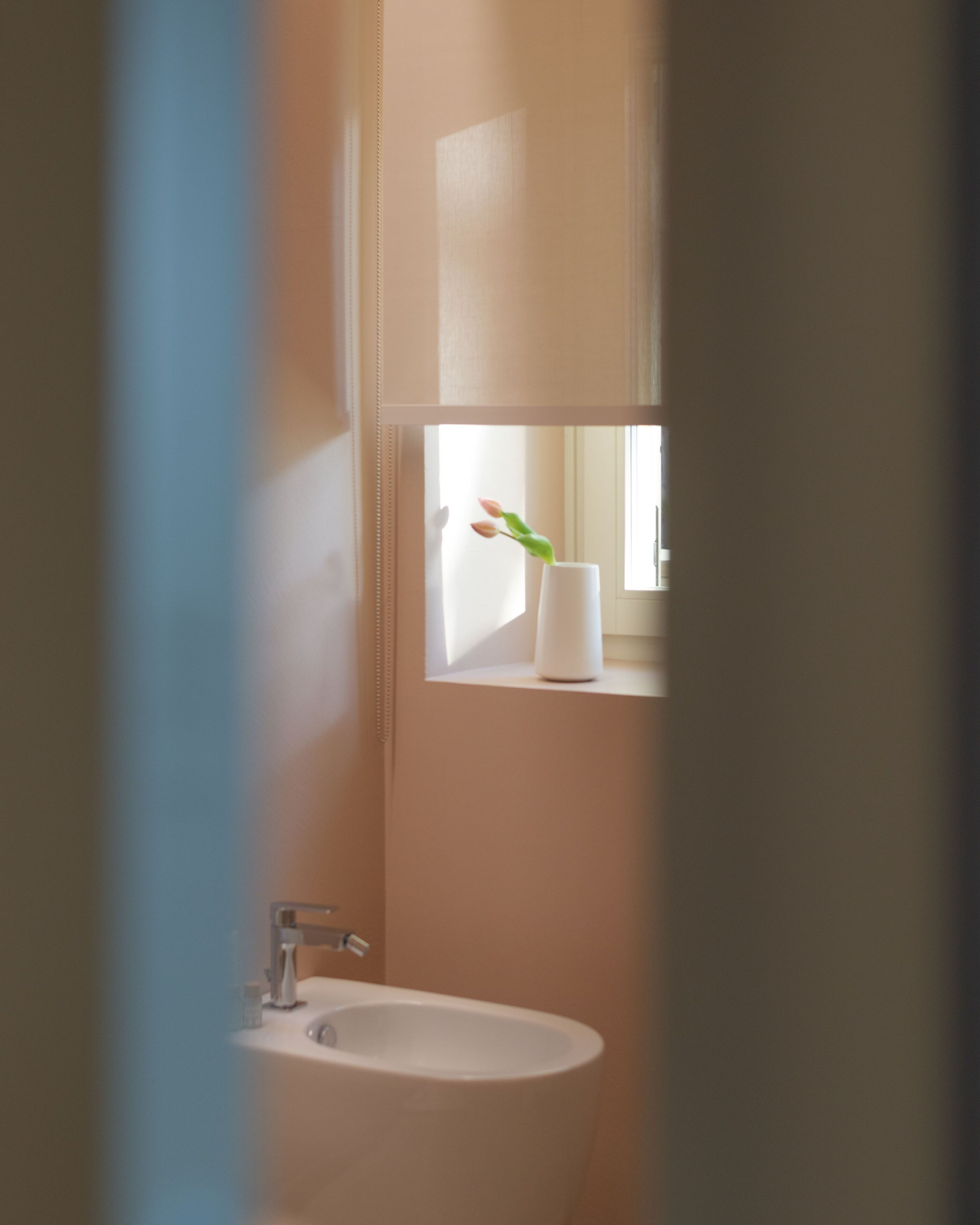 Un baño con lavamanos, espejo y ventana con planta.