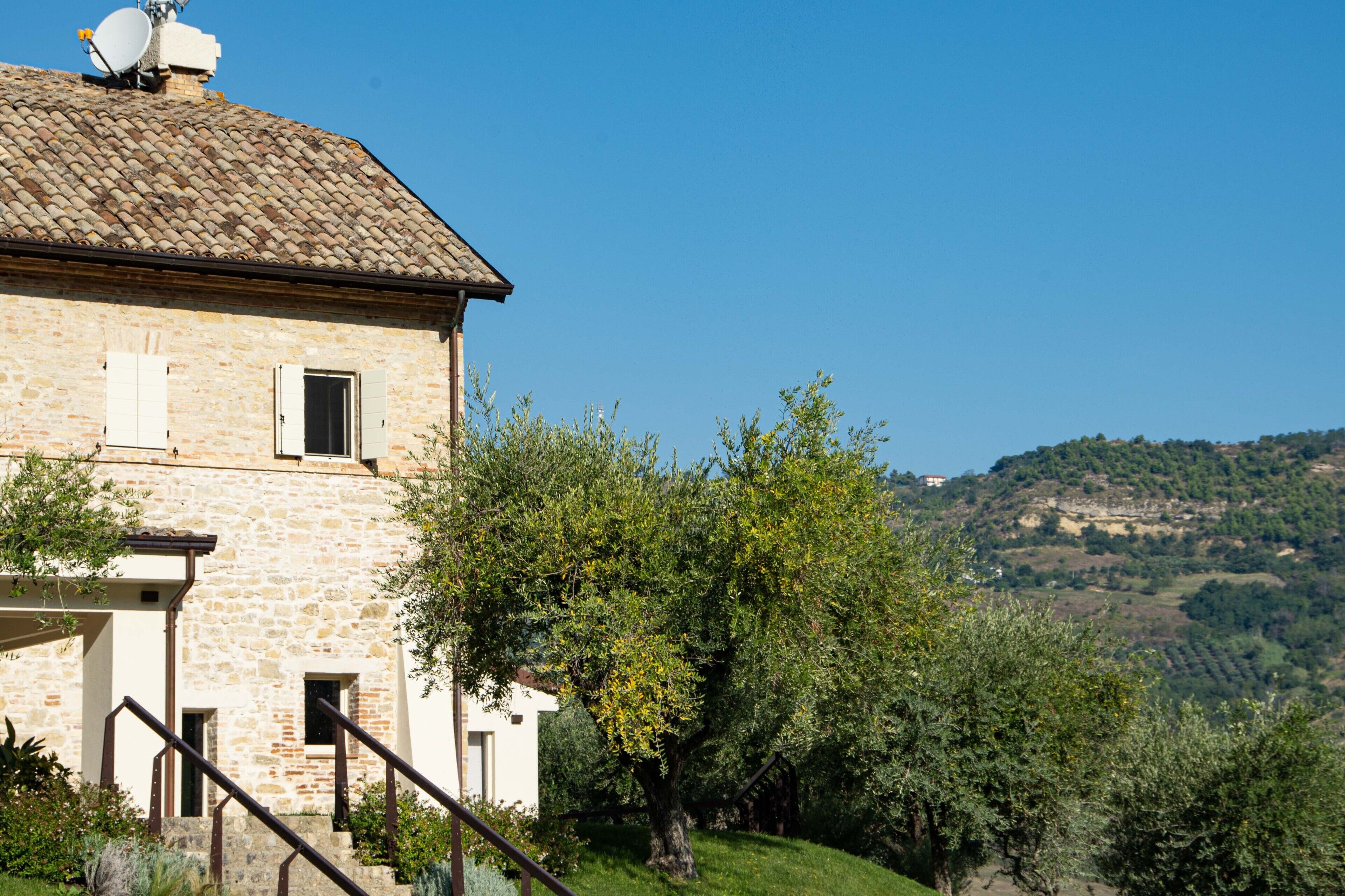 Un bâtiment en pierre avec un toit en tuiles, un escalier et une vue sur une colline.