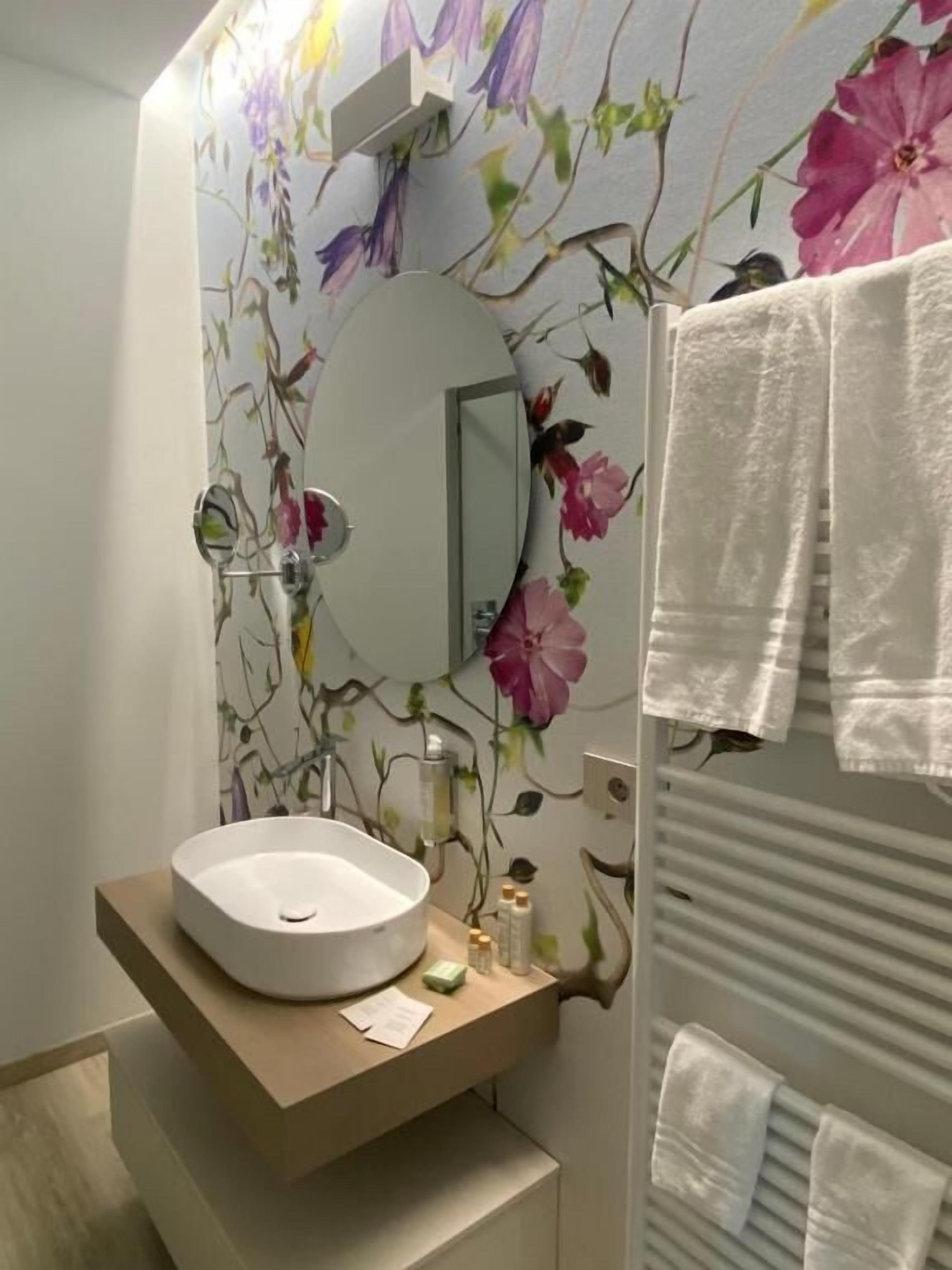 A bathroom with a round sink, a mirror, and a towel rack.