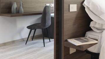 Un dormitorio moderno con cabecera de madera, una mesita de noche con un libro, una silla y un estante con objetos decorativos.