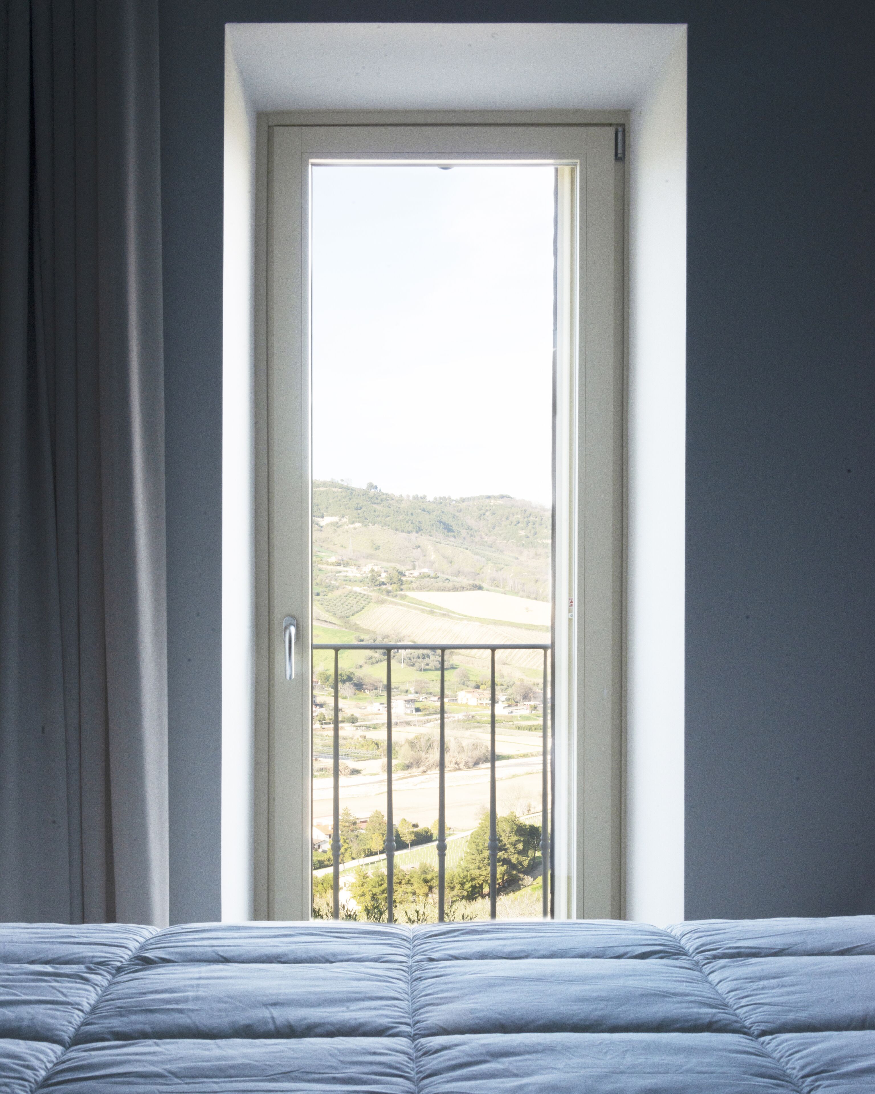 Une chambre à coucher avec un lit, une fenêtre donnant sur un paysage et une porte.