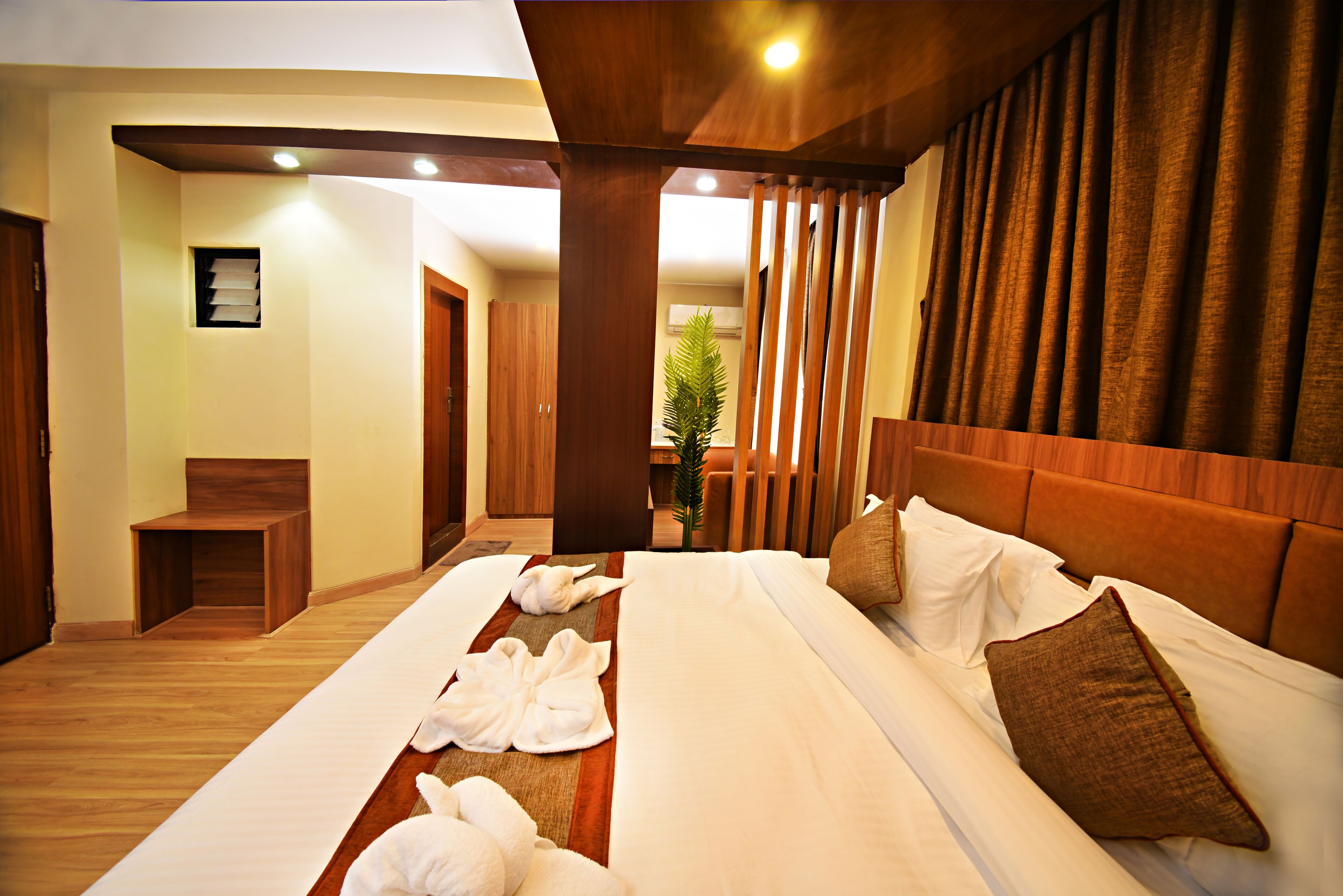 Una habitación de hotel con una cama grande, cabecera de madera y un pequeño rincón de estar.
