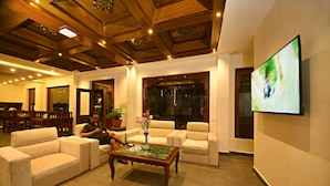 A modern living room with a wooden ceiling, a flat-screen TV, and a sofa set. - Capital Boutique Hotel (Kathmandu)