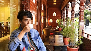A man sitting at a table with a potted plant and a vase of flowers. - Capital Boutique Hotel (Kathmandu)