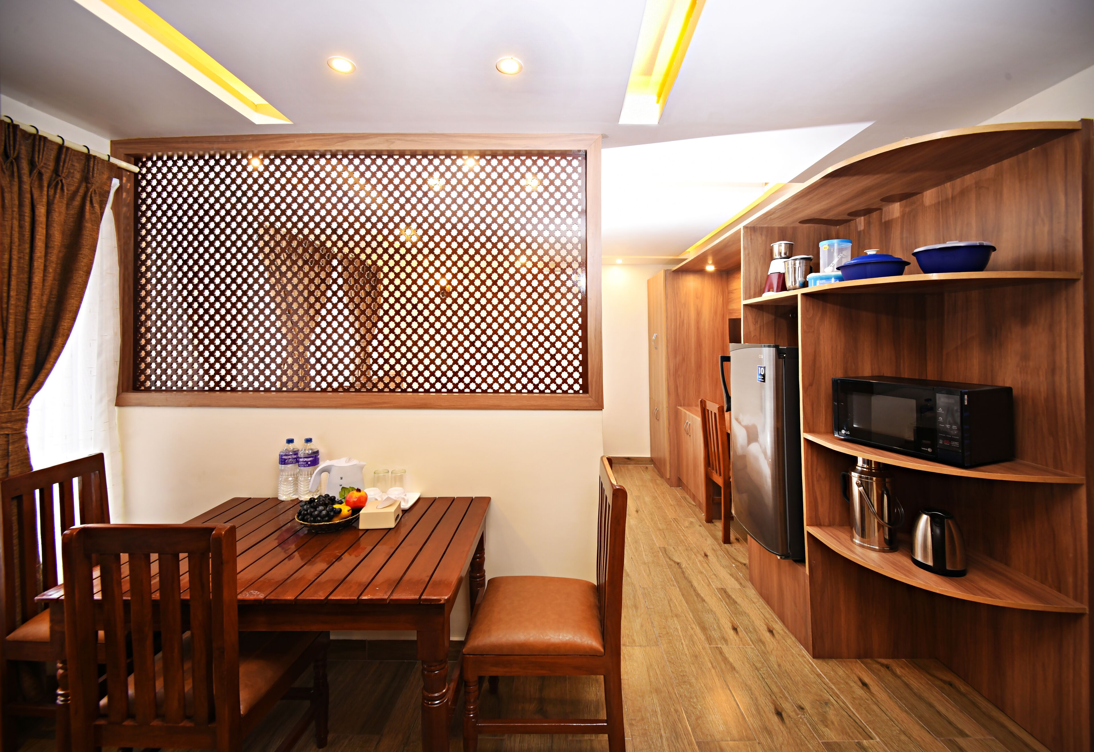 Une cuisine compacte avec des meubles en bois, une table à manger, des chaises et un réfrigérateur.