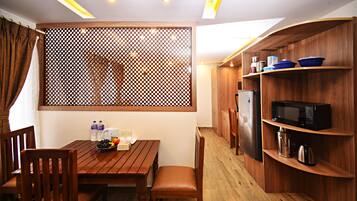 Une cuisine compacte avec des meubles en bois, une table à manger, des chaises et un réfrigérateur.