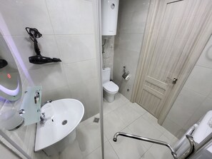 A bathroom with a white sink, toilet, and shower area. - Black Sea Apartments Alliance Palace (Batumi)