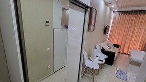 A modern living room with a sofa, chairs, a coffee table, and a TV. - Black Sea Apartments Alliance Palace (Batumi)