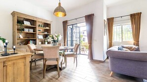 Een ruime woonkamer met een houten eettafel, stoelen, een bank en een boekenkast.