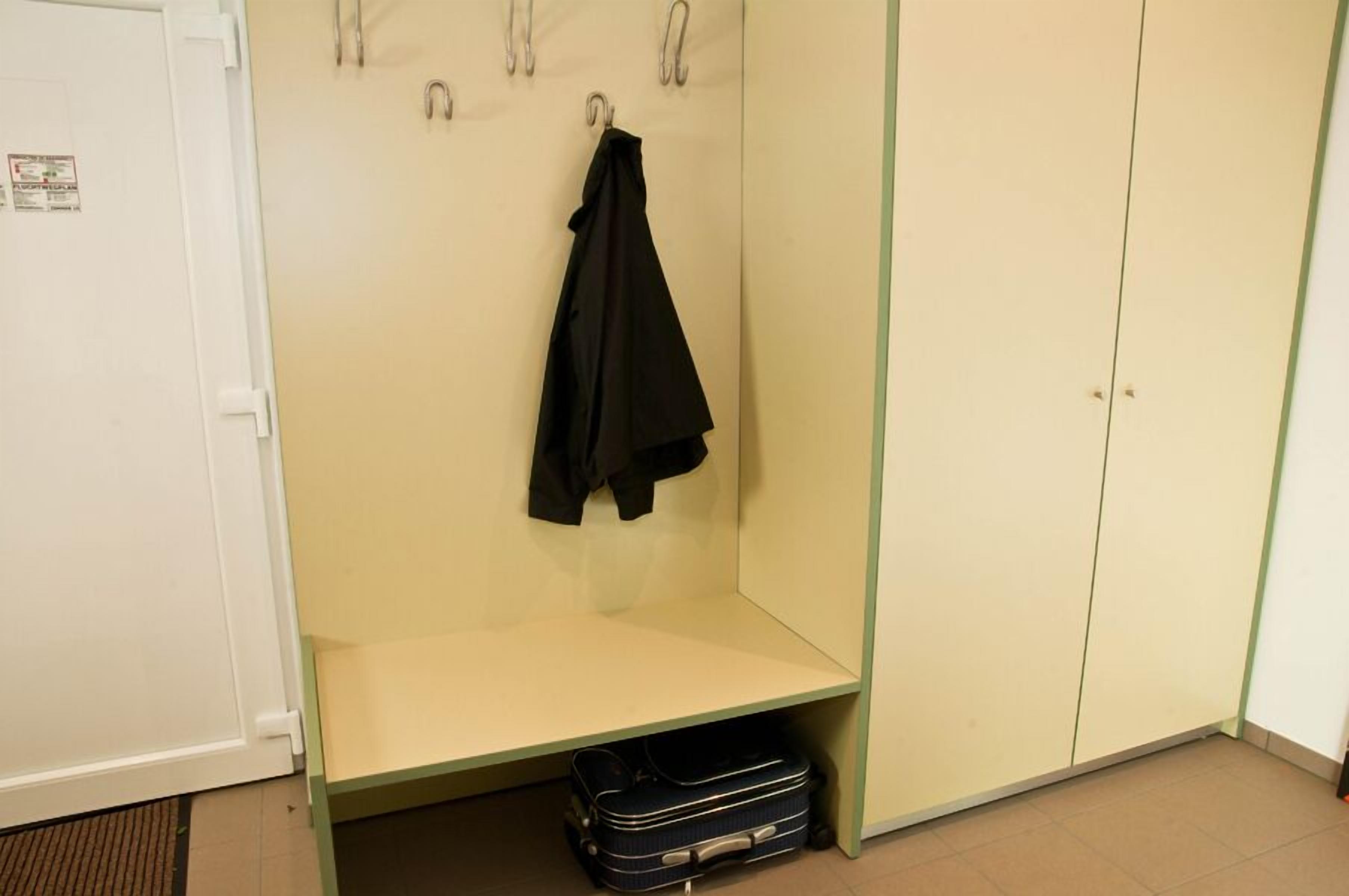 A room with a wardrobe, a bench, and a hanging coat rack.