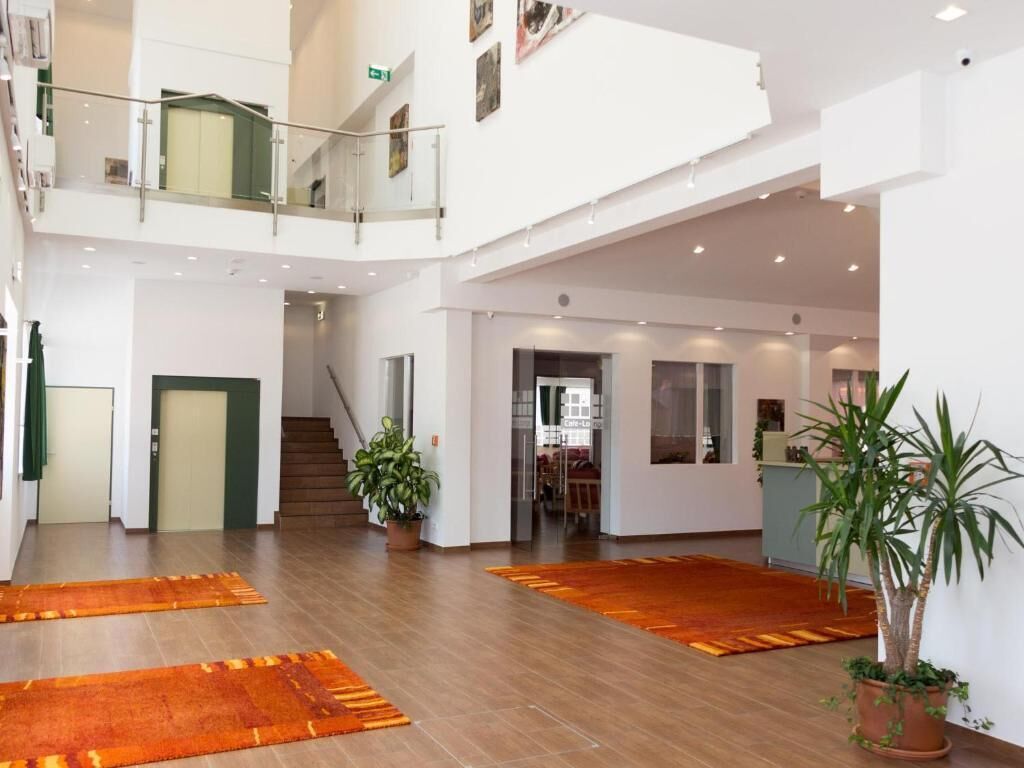 A spacious, multi-level interior with wooden flooring, potted plants, and a staircase leading to an upper level.
