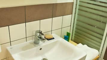 A bathroom with a white sink, a mirror, and a shower area.