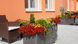 A building with a row of windows and a planter with red and yellow flowers. - Winrooms (Wiener Neustadt)