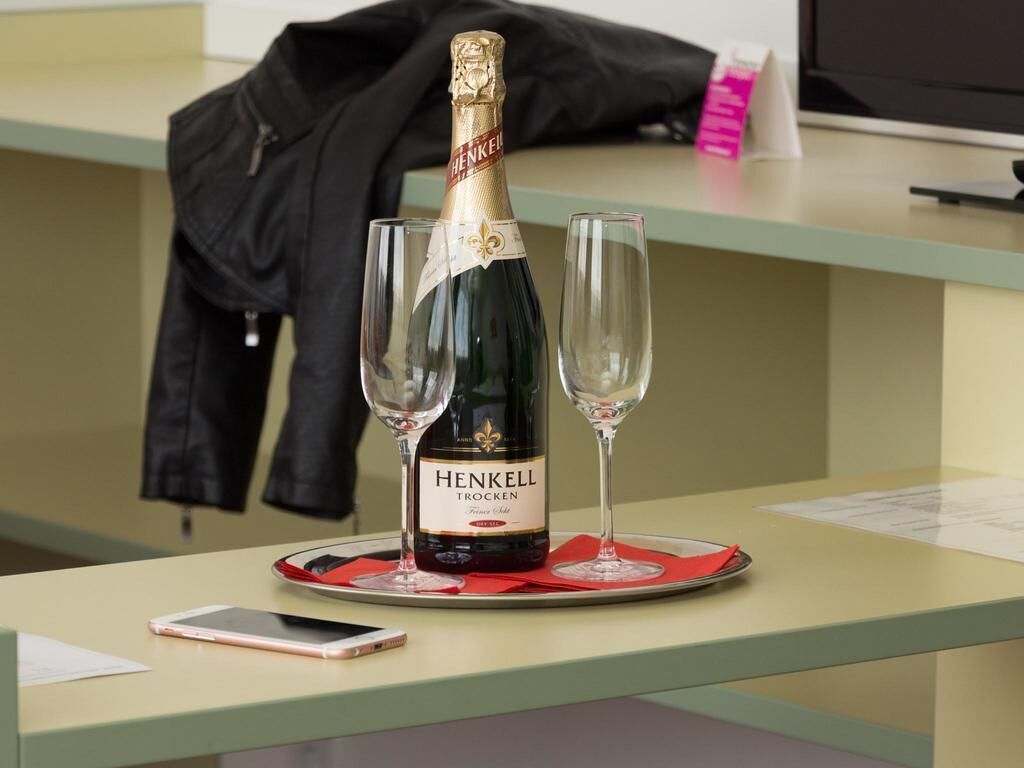 En flaske Henkell Trocken champagne med to glas på et fad.
