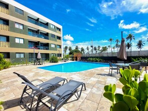 Un hotel con piscina, mobiliario exterior y vistas a palmeras.