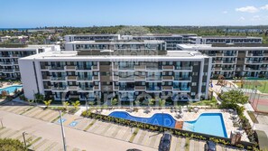A modern multi-story hotel with a swimming pool, outdoor seating, and a view of the ocean. - Mana Beach Experience- Porto de Galinhas (Ipojuca)