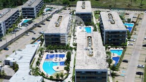 A multi-story hotel with a rooftop pool area, parking spaces, and a landscaped garden. - Mana Beach Experience- Porto de Galinhas (Ipojuca)