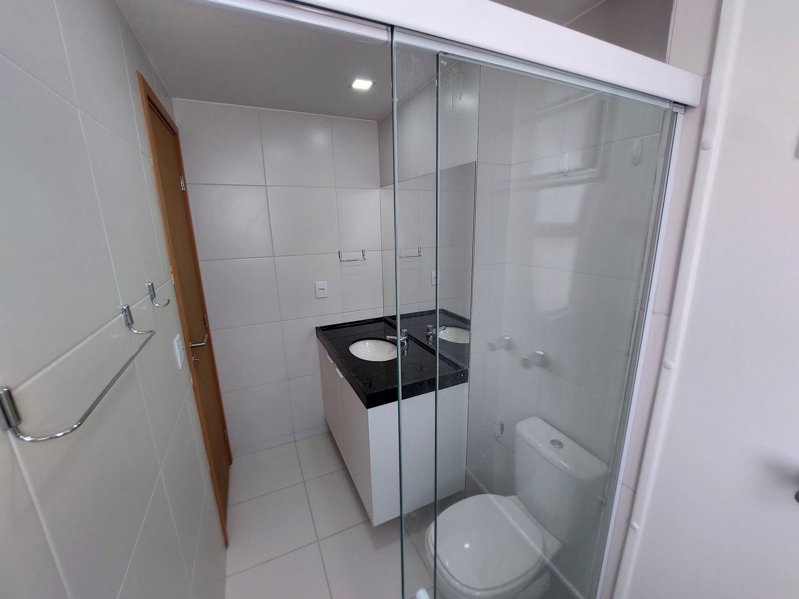 A bathroom with a glass-enclosed shower, a white toilet, and a black countertop sink.