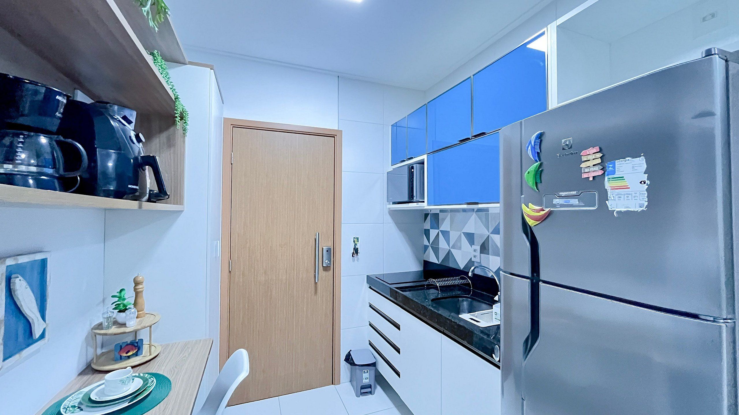 Une cuisine compacte équipée d’un four à micro-ondes, d’un réfrigérateur et d’un petit coin repas avec une table et des chaises.