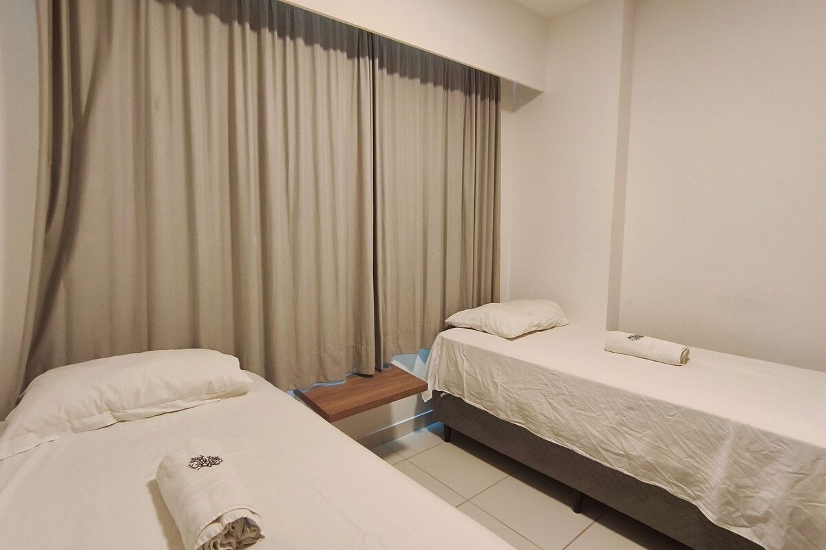 A hotel room with two single beds, a wooden nightstand, and a window with curtains.
