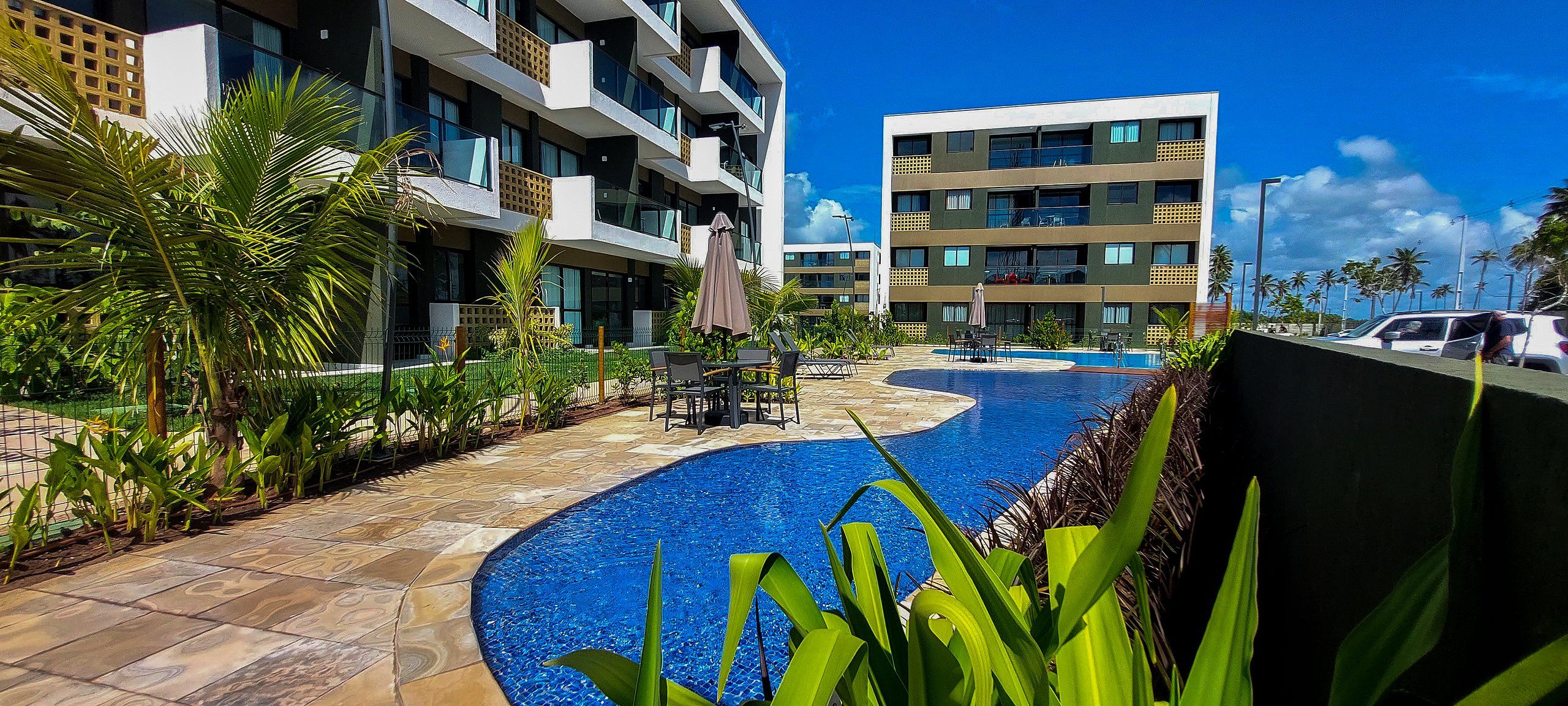 A hotel with a swimming pool, outdoor seating, and a view of the surrounding buildings.