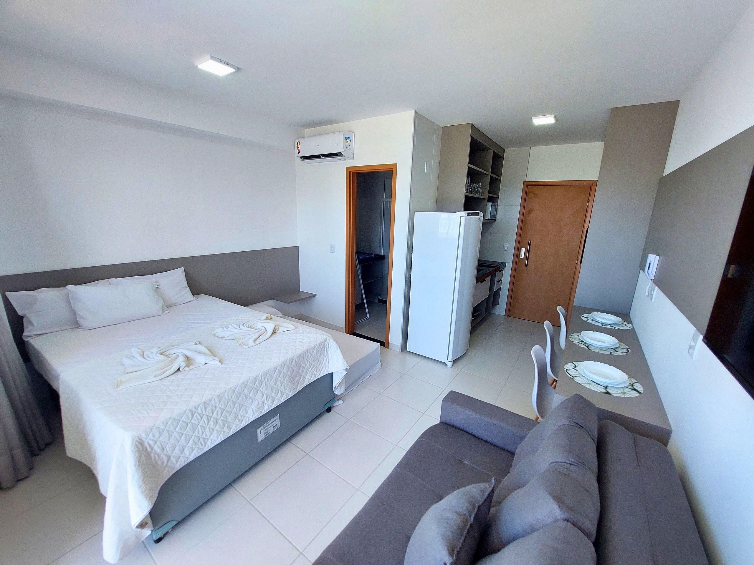 Een hotelkamer met een bed, een bank, een kitchenette en een airconditioning.