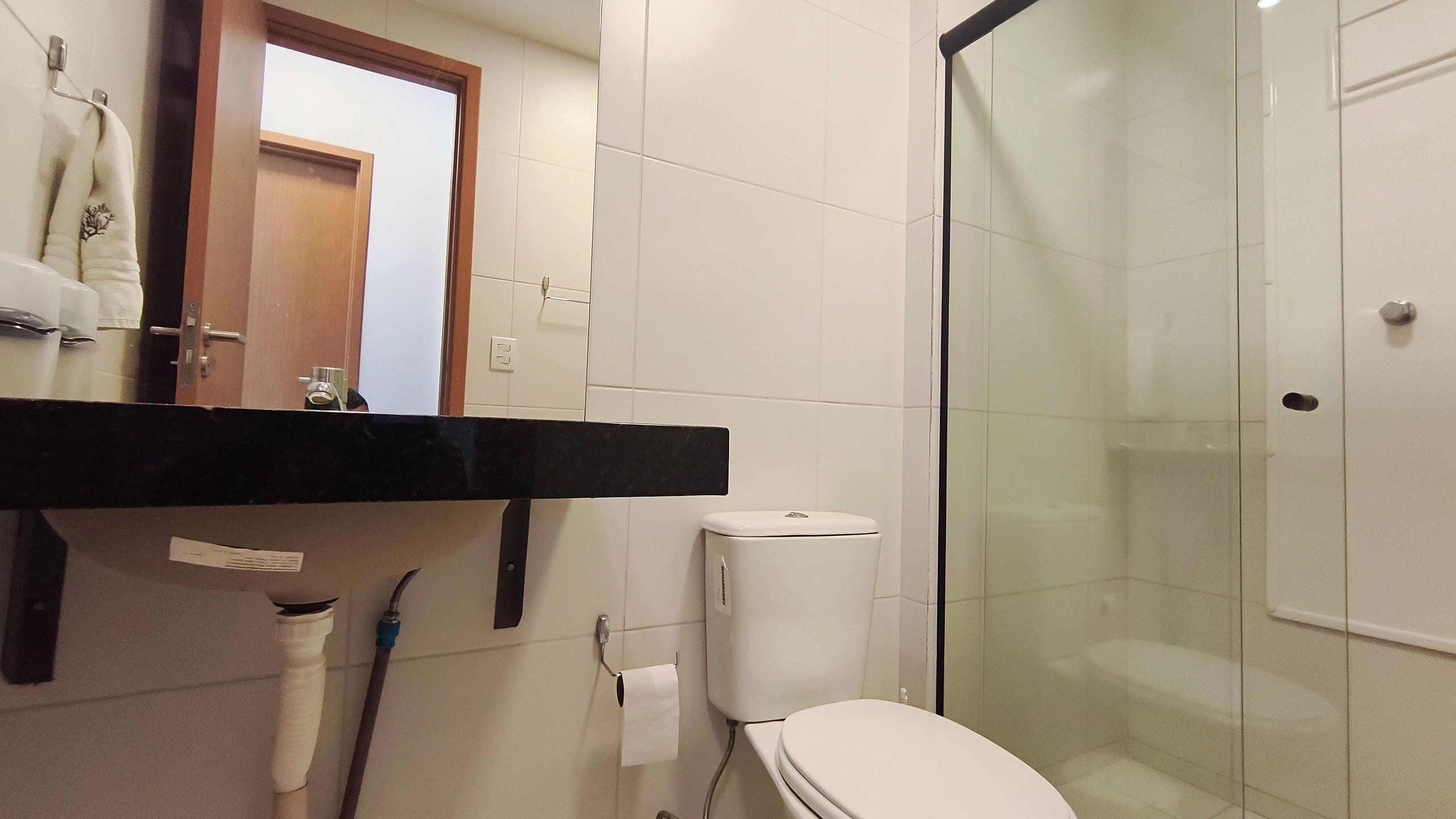 Un baño con inodoro, ducha con puerta de cristal, toallero y espejo.