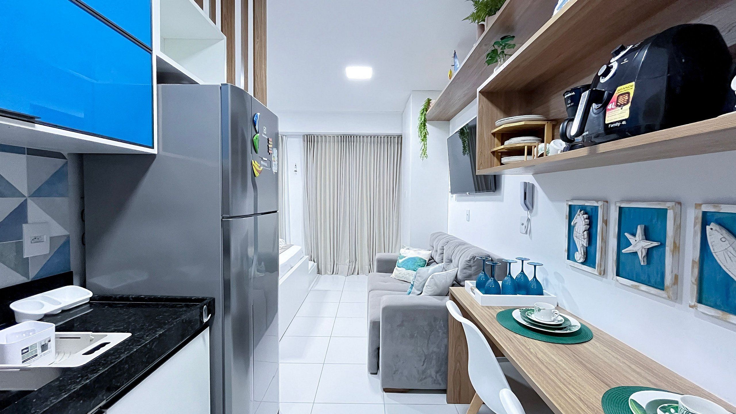 Una cucina moderna con frigorifero, un'area pranzo con tavolo e sedie e un soggiorno con divano.
