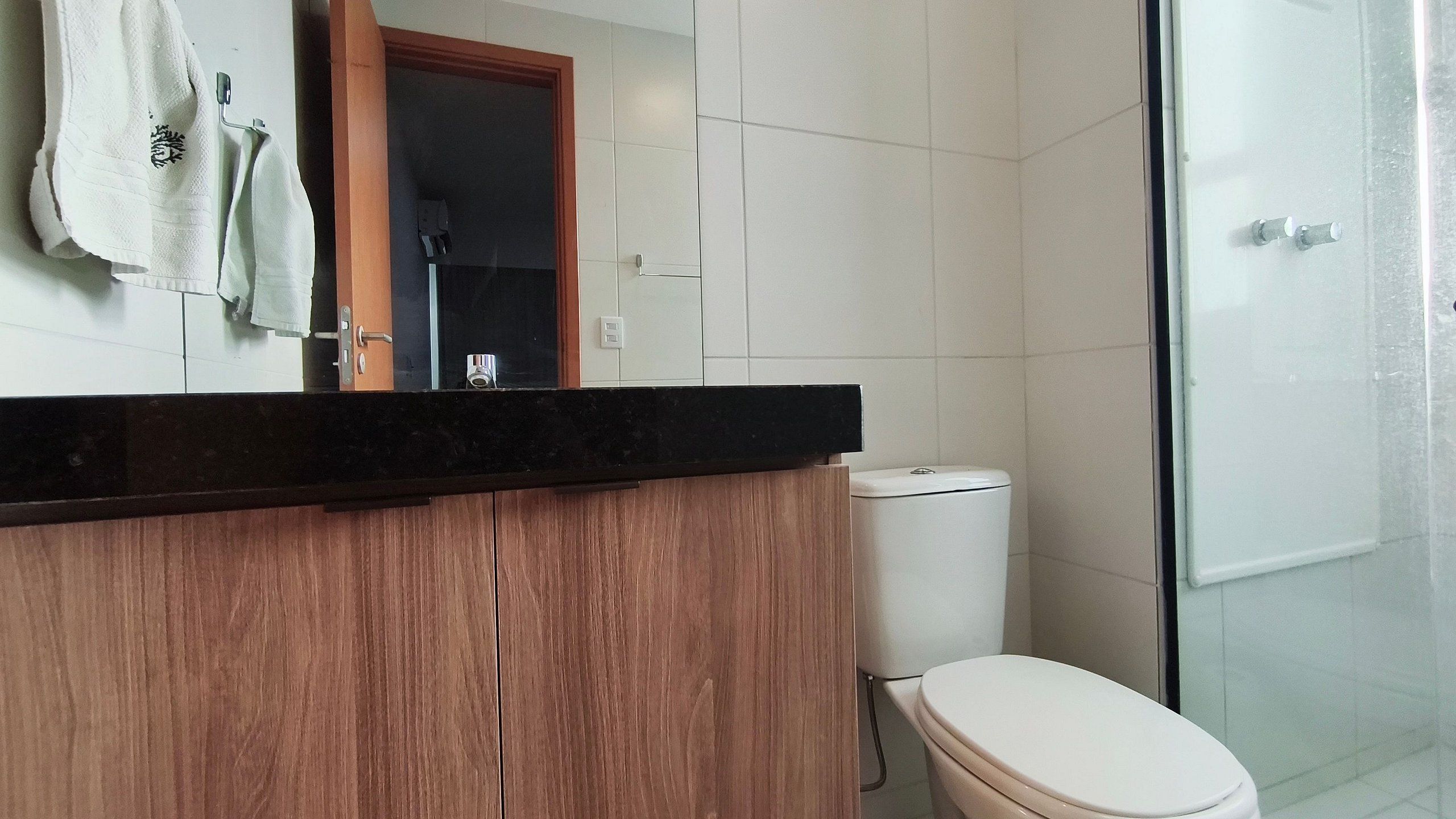 Un bagno con un mobile bagno in legno, un water e uno sporto doccia in vetro.