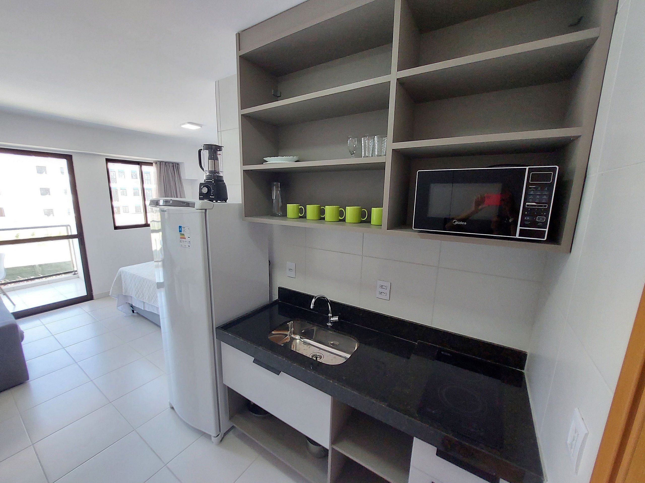 A modern kitchen with a refrigerator, microwave, and a coffee maker on the counter.
