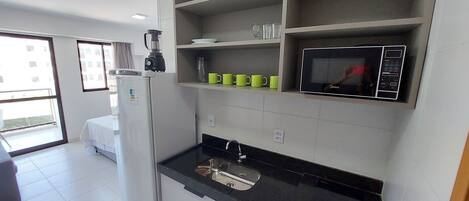 A modern kitchen with a refrigerator, microwave, and a coffee maker on the counter.