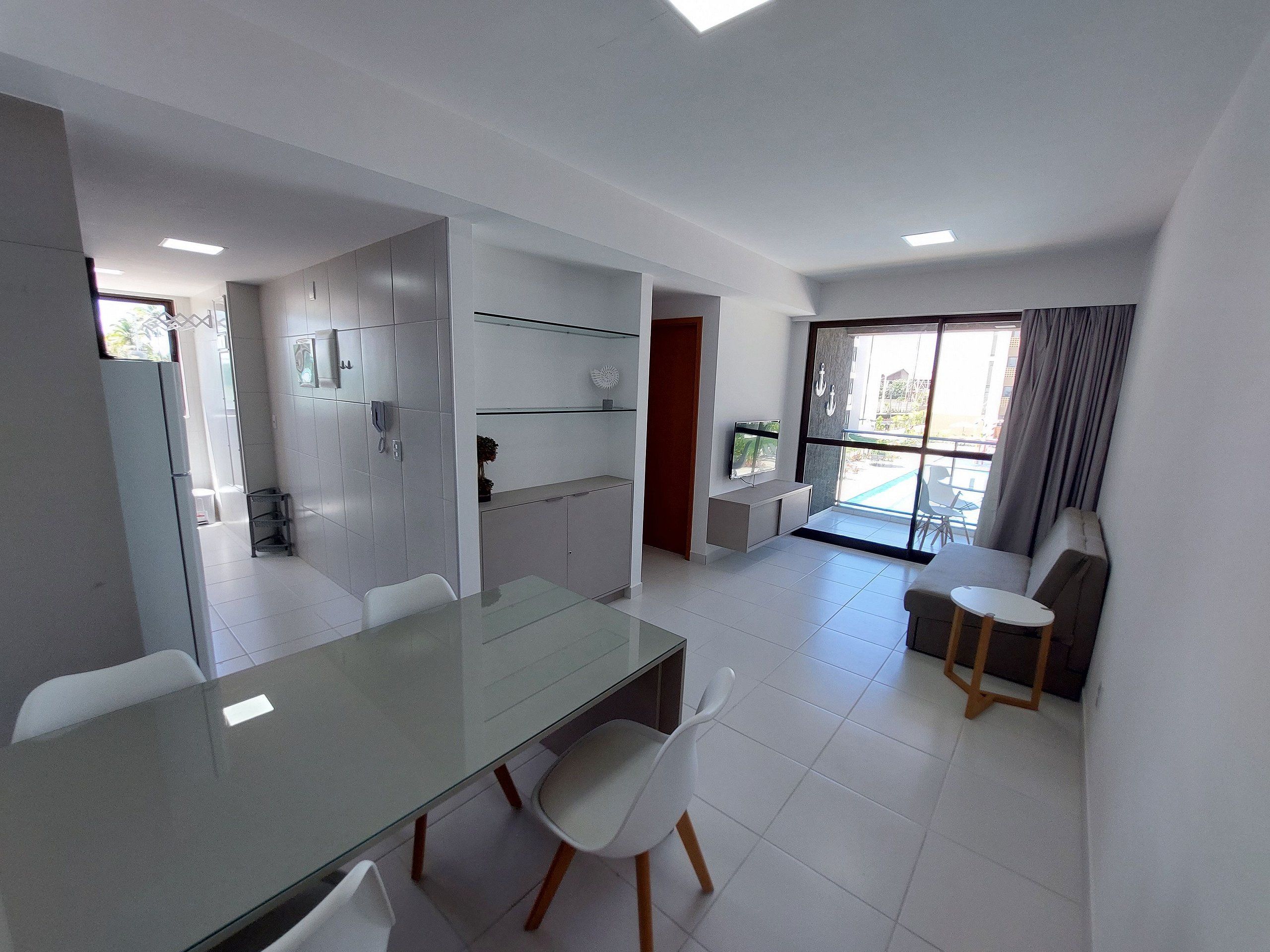A modern kitchen with white cabinets, a glass dining table, and a built-in oven.