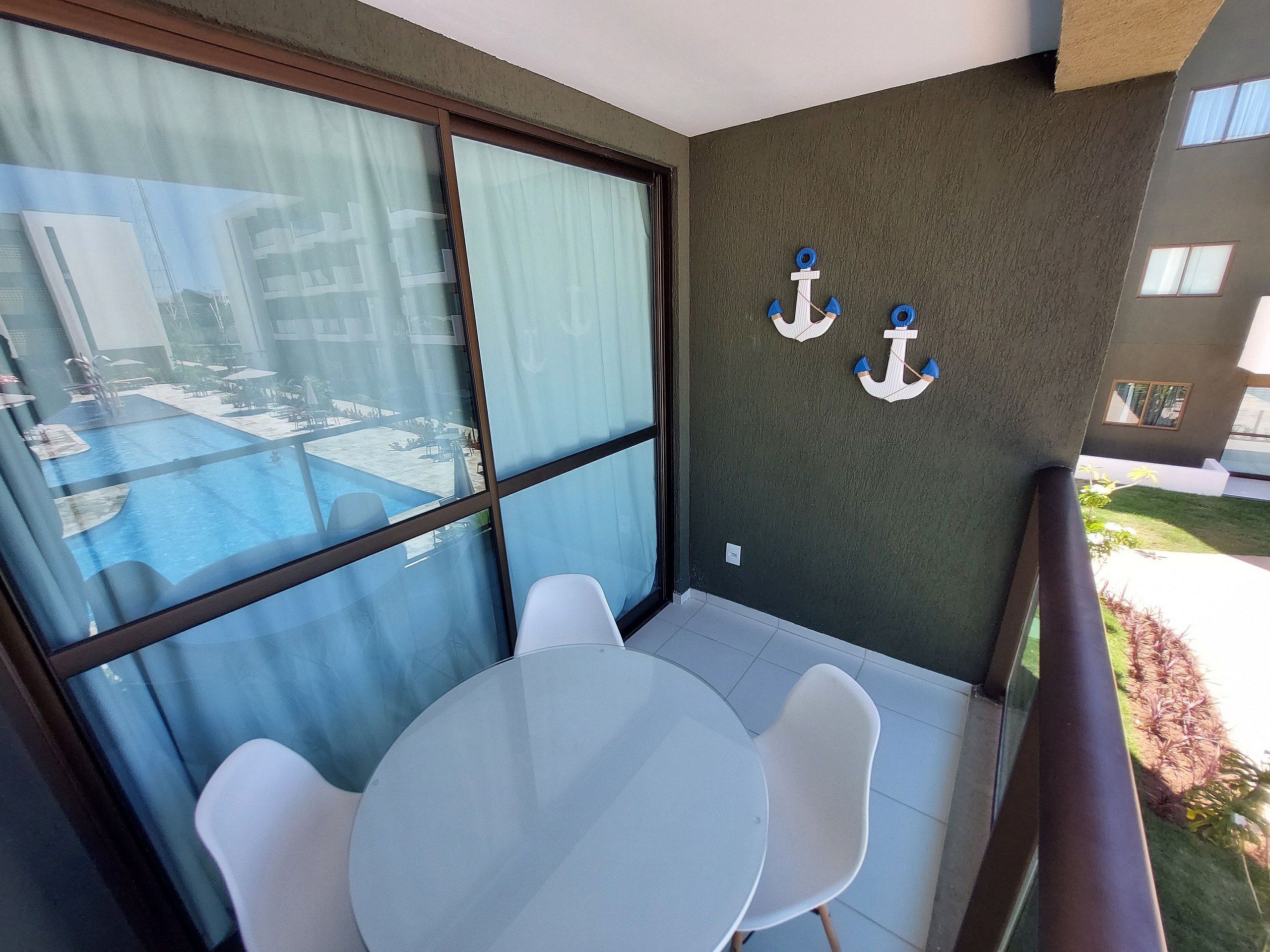 A balcony with a glass door, a pool view, and two white chairs.