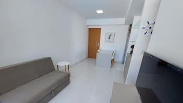 Una sala moderna con un sofá, una mesita, un comedor y una cocina con encimera negra.