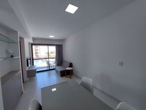 A modern hotel room with a balcony, a dining area, and a TV. - Mana Beach Experience- Porto de Galinhas (Ipojuca)