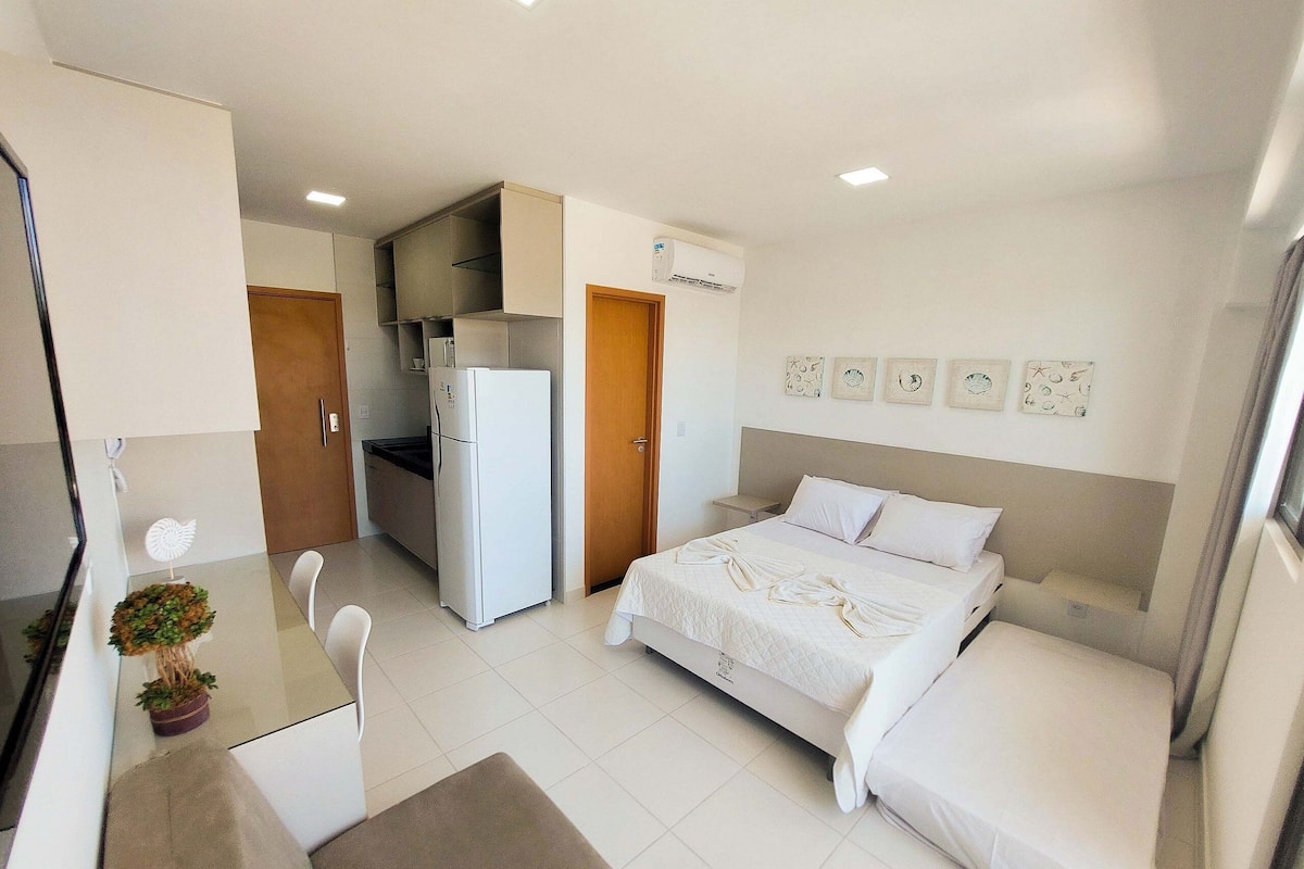 Habitación de hotel compacta con cama, kitchenette pequeña, zona de comedor y baño.