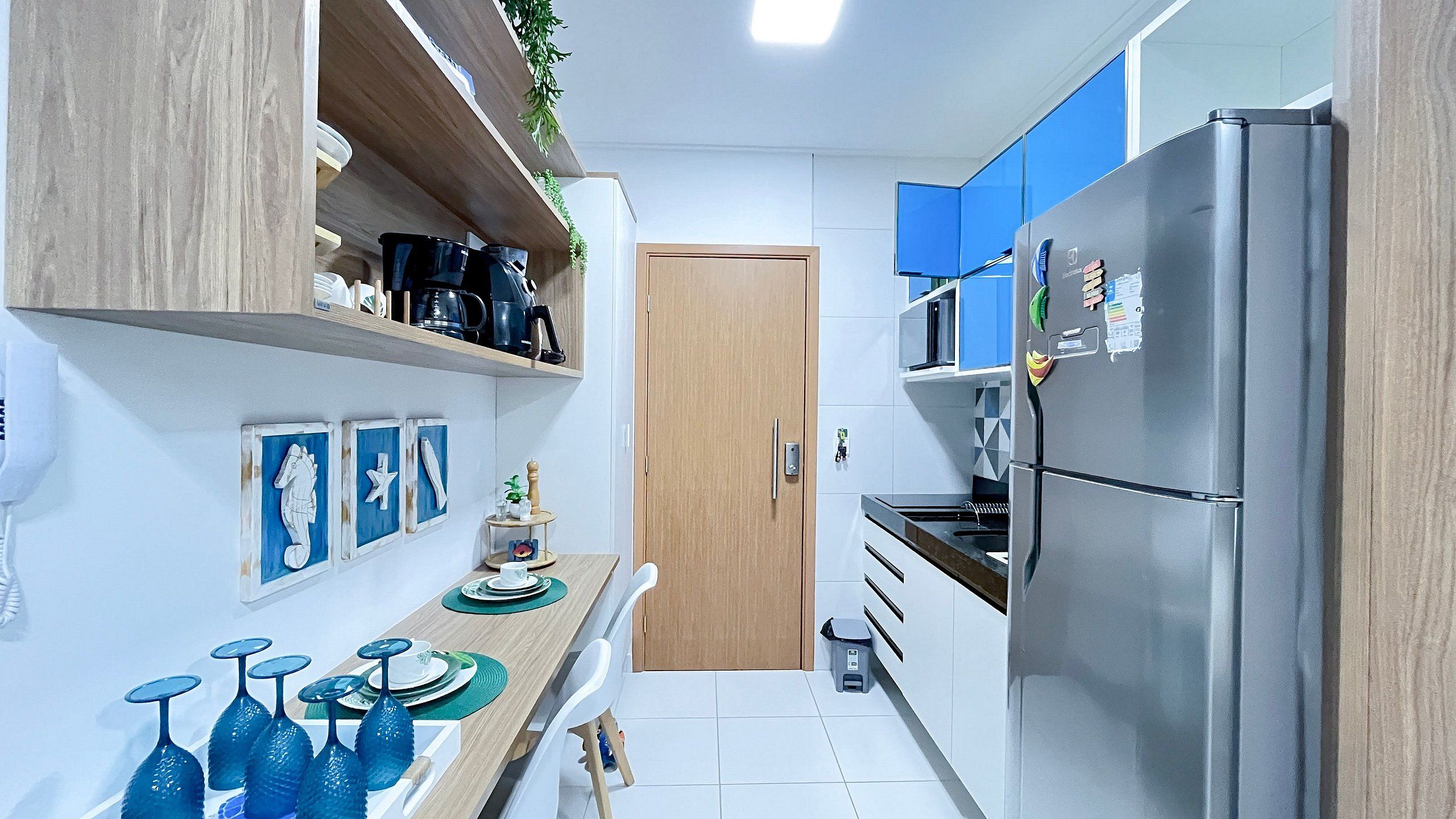 Cocina estrecha con refrigerador, microondas y armarios de madera.