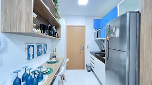 A narrow kitchen with a refrigerator, microwave, and wooden cabinets.