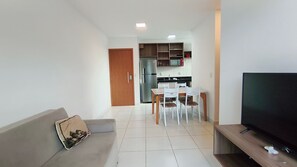 A living room with a sofa, a TV, and a dining area with chairs and a table. - Mana Beach Experience- Porto de Galinhas (Ipojuca)