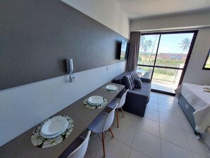 A modern hotel room with a dining area, a sofa, and a bed. - Mana Beach Experience- Porto de Galinhas (Ipojuca)