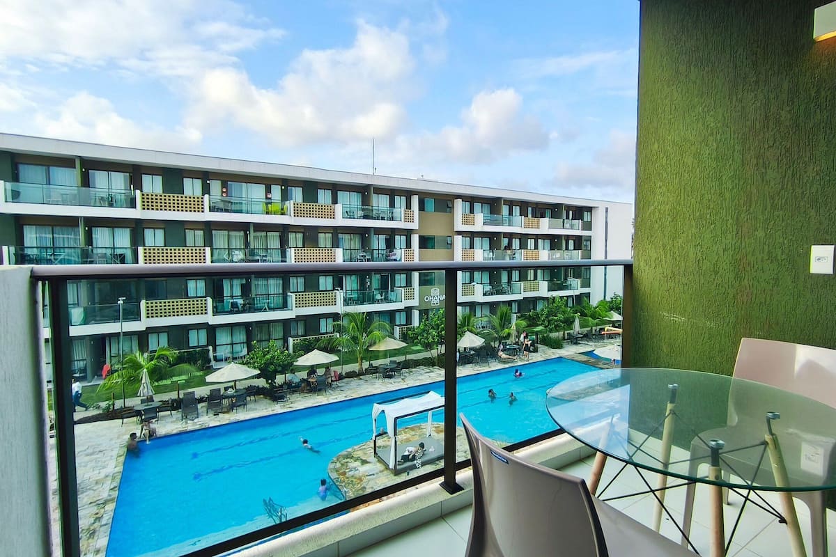 Um hotel moderno com varanda de vidro com vista para a área da piscina.