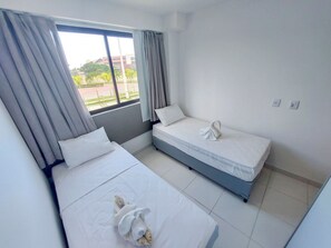 Habitación de hotel con dos camas, una ventana con cortinas y vistas al exterior.