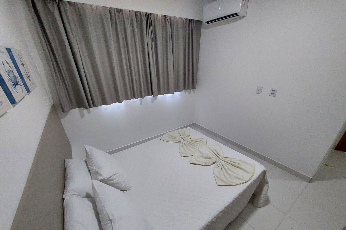 A small, single-bed room with a grey curtain, a wall-mounted air conditioner, and a simple, clean design.