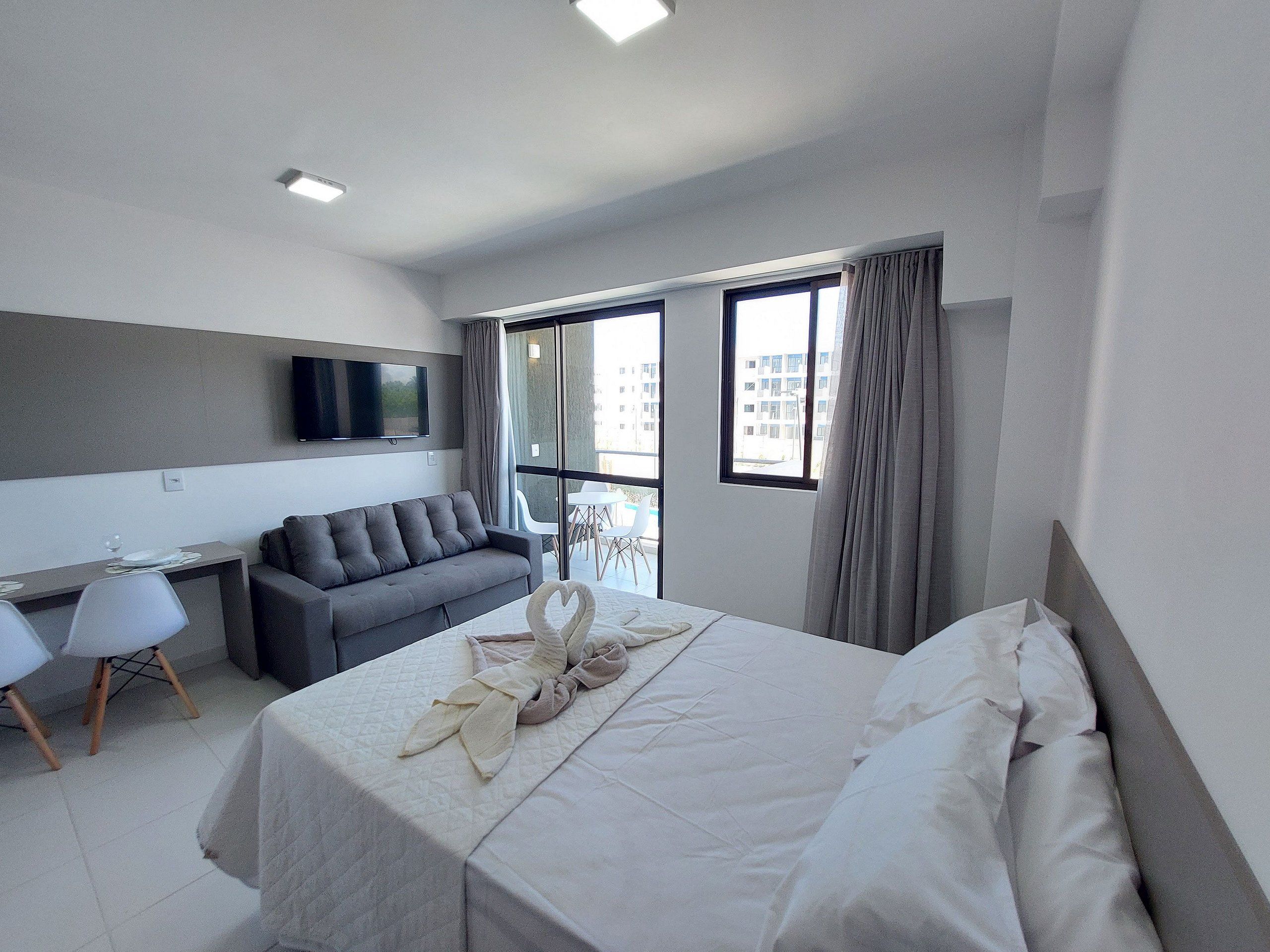 Una habitación de hotel moderna con cama, sofá, escritorio y televisor.