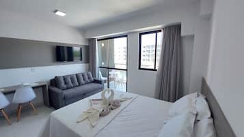 Una habitación de hotel moderna con cama, sofá, escritorio y televisor.
