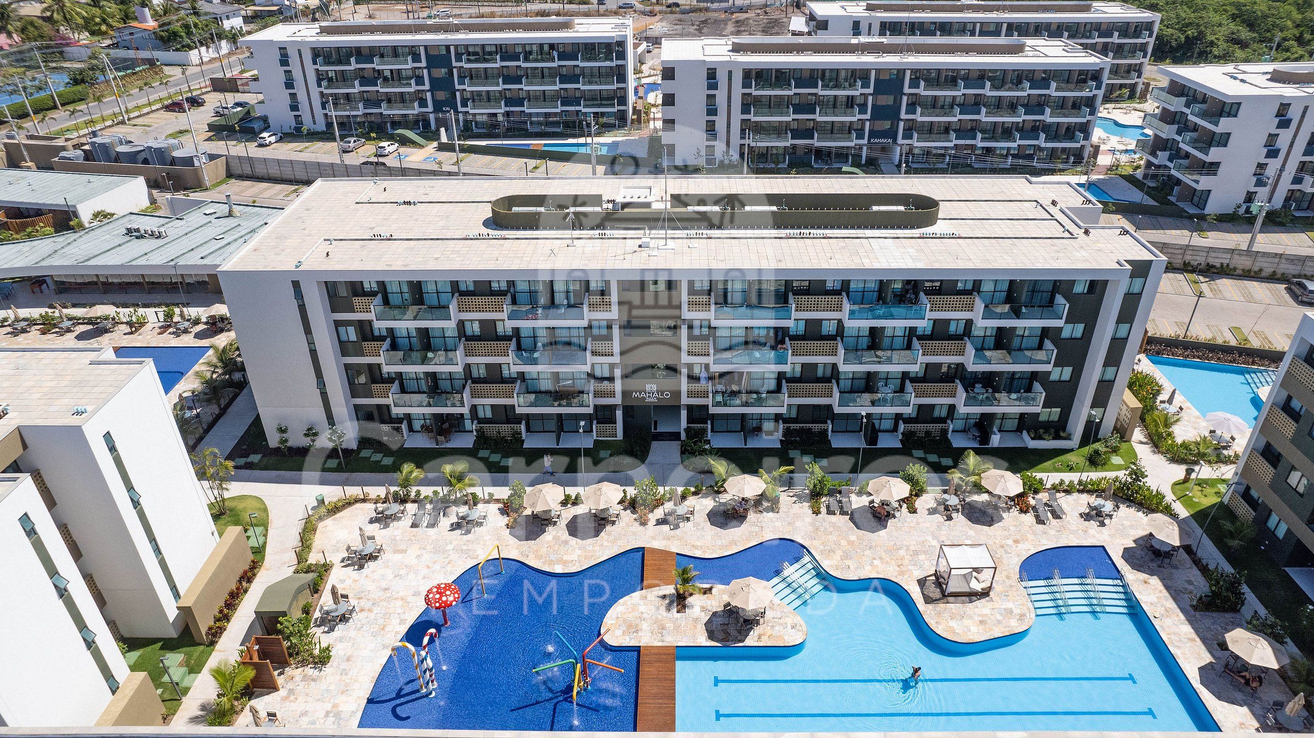 Um hotel moderno com várias varandas, piscina e áreas de estar ao ar livre.