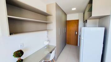 Cocina estrecha con refrigerador, una mesa de vidrio y una planta en maceta.