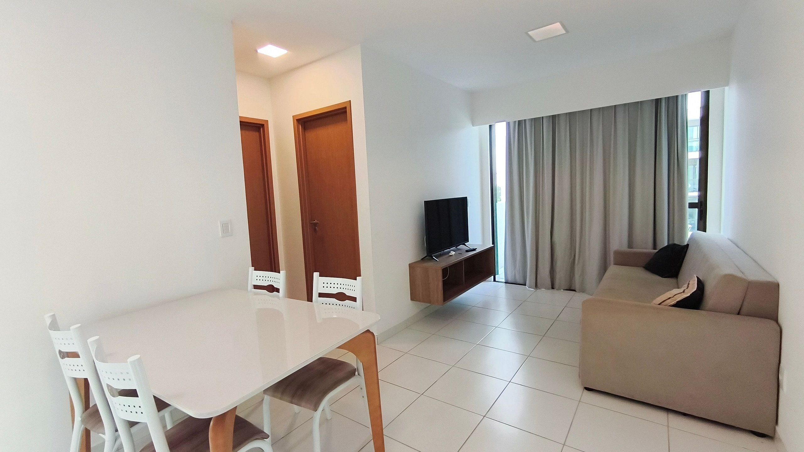 Una sala de estar con sofá, televisión y comedor con sillas y una mesa.
