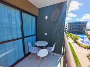 A balcony with a view of a swimming pool and a building. - Mana Beach Experience- Porto de Galinhas (Ipojuca)