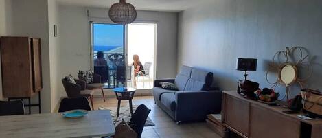 A modern living room with a dining area, a sofa, a coffee table, and a TV on a wooden cabinet.